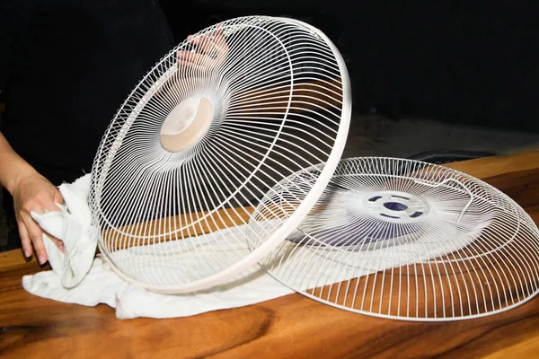 El ama de llaves usa un paño blanco Limpie y limpie el ventilador eléctrico . —  Fotos de Stock