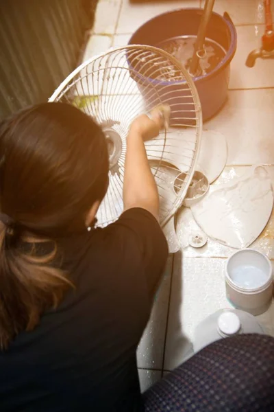 家庭主妇使用白布擦拭和清洁电风扇. — 图库照片