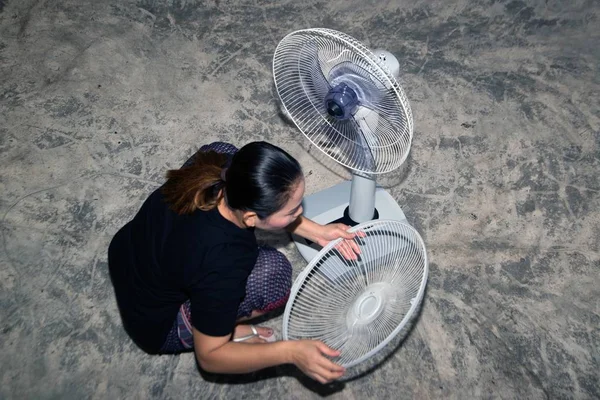 The housekeeper is assembling and installing an electric fan after cleaning.