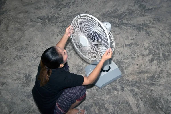 The housekeeper is assembling and installing an electric fan after cleaning.