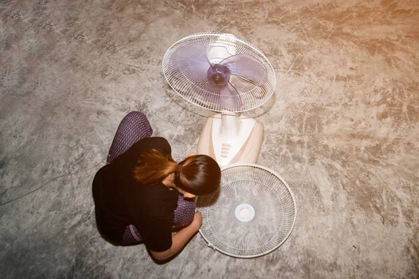 The housekeeper is assembling and installing an electric fan after cleaning.