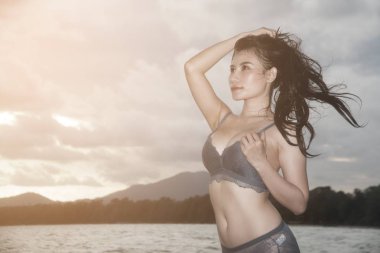 Mavi bikinili Pretty Asyalı kadın sahilde eğlenceli poz.