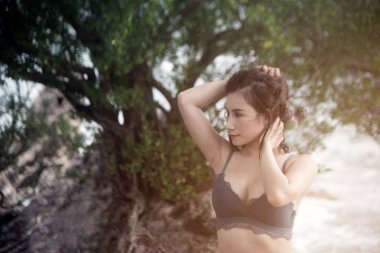 Mavi bikinili Pretty Asyalı kadın sahilde eğlenceli poz.