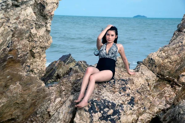 Mujer asiática bonita en traje de baño posando en la piedra de la playa . — Foto de Stock