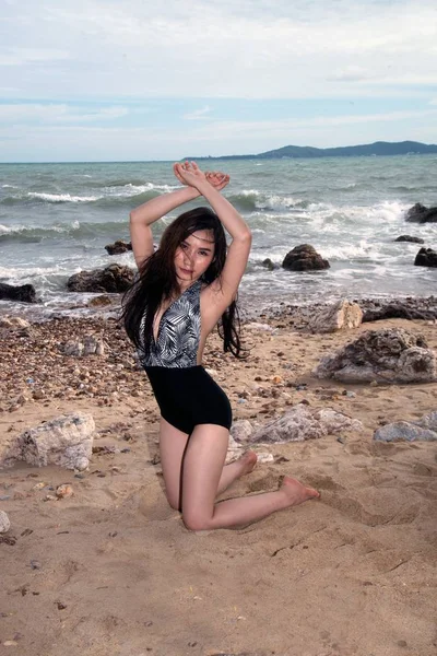 Mulher asiática bonita em maiô posando na pedra da praia . — Fotografia de Stock