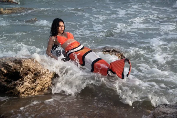 Pretty Asian woman in bikini with Mermaid dresses on fun at a beach.