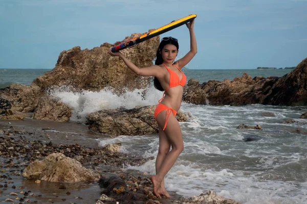 Hübsche asiatische Frau im Bikini mit Surfbrett auf Spaß, Surfbrett ist Wassersportunterricht und Strandschwimmen Aktivität im Sommerurlaub. — Stockfoto