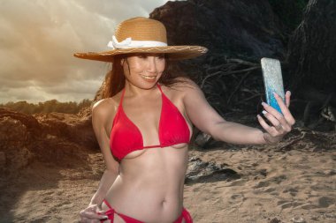 Bir cep telefonu mayo asyalı bir kadın kendini pozlar, o sahilde bir akıllı telefon ile selfie alıyor.