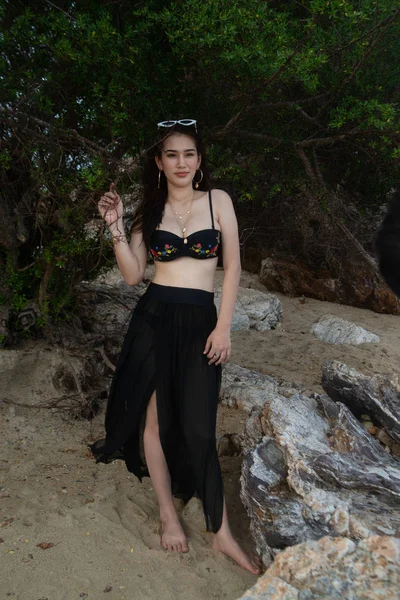 Όμορφο ασιατικό θηλυκό σε ένα μαύρο μαγιό στέκεται σε μια παραλία. — Φωτογραφία Αρχείου
