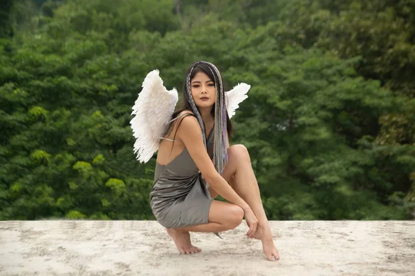 En vacker asiatisk kvinna har en fågelvinge på baksidan av sittande pose. — Stockfoto