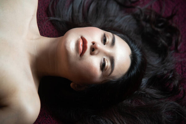 Sensual nude Asian women sensuality lying on the red floor.