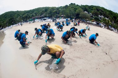 RAYONG, THAILAND-FEBRUARY 8. 2013: Tayland 'da Khao Laem Ya-Mo Ko samet Ulusal Parkı' ndaki Prew sahilindeki büyük bir plastik torba içinde ham petrolle kumu küreyen tanımlanamayan işçiler ve gönüllüler.