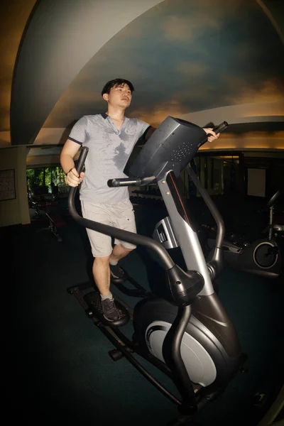 The young Asian male in exercise clothes by running on the treadmill in the gym.The sport and healthy lifestyle concept.