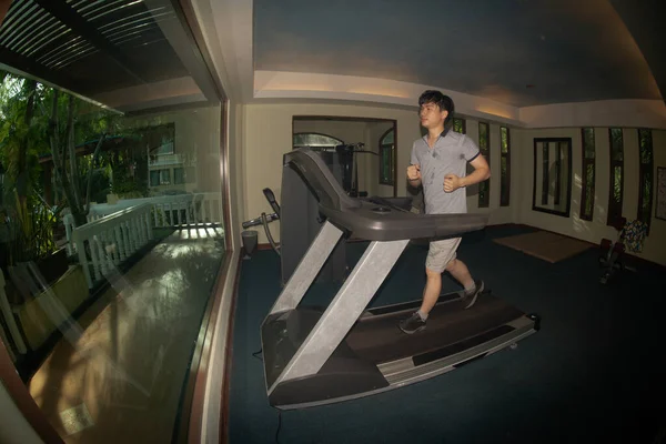 The young Asian male in exercise clothes by running on the treadmill in the gym.The sport and healthy lifestyle concept.