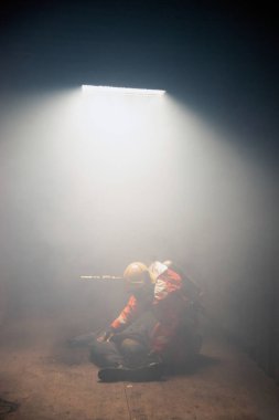 İtfaiyeciler yanan ve dumanlı bir binada insanlara yardım ediyor..