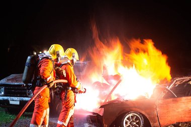 İtfaiyeciler arabada çıkan yangını söndürmek için su püskürtüyorlar..