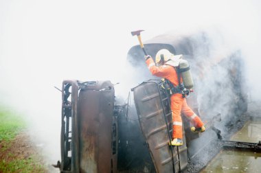 İtfaiyeciler balta kullanıyor. Yanan ve dumanlı bir kamyondaki engelleri yok ediyorlar..
