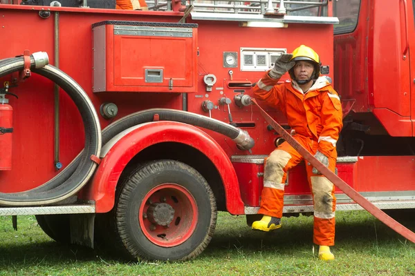 The fireman is preparing to put out the fire at the fire engine. Because the fire was burning in the building.