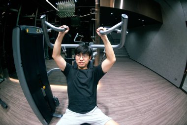 Jimnastik yaparken göğüs kasları için egzersiz yapan Asyalı bir erkek. Spor ve sağlıklı yaşam tarzı konsepti.. 