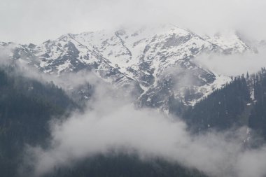 The Himalayas, shrouded in mist, create a beautiful view from Pahalgam, a place surrounded by lush pine forests in Jammu and Kashmir, India.