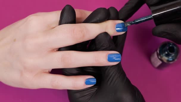 Manicura pinta las uñas de los clientes con esmalte de uñas de tinte azul — Vídeos de Stock