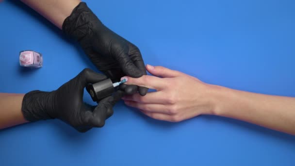 Manicurista pinta las uñas de los clientes con esmalte de uñas protector transparente — Vídeo de stock