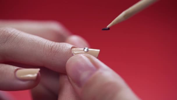 Macro shot con manicure che attacca strass alle unghie dipinte — Video Stock