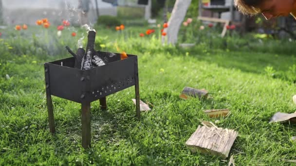 Homme coupe le bois par la hache et le met dans un barbecue de feu à l'arrière-cour — Video