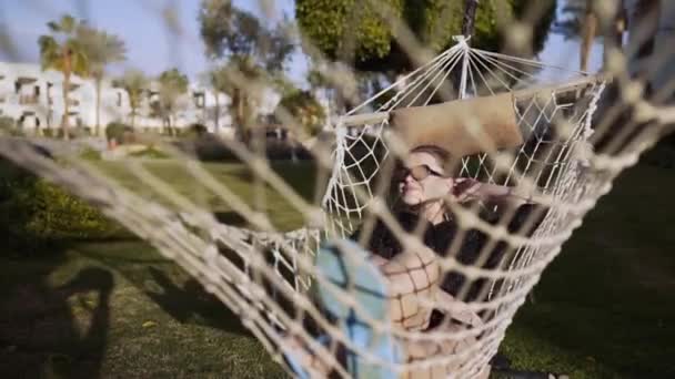 Žena mrazí v houpací síti při západu slunce — Stock video