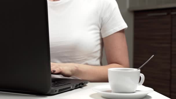 Frau arbeitet am Arbeitsplatz am Laptop und trinkt Kaffee Stockvideo
