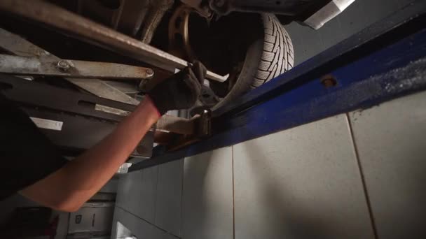 Mecánico se para en el foso y comprueba la suspensión en la estación de servicio del coche — Vídeo de stock