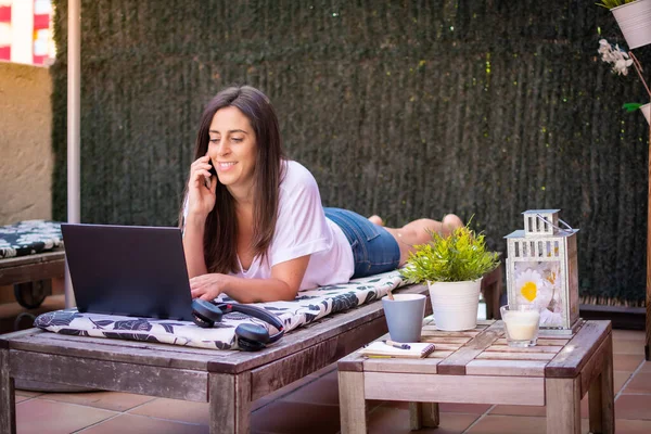 Woman freelancer, travel blogger works on a laptop. sitting on a lounger in the garden