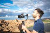 mladý filmař natáčející přírodní krajinu v kaňonu s velkou řekou a bažinami