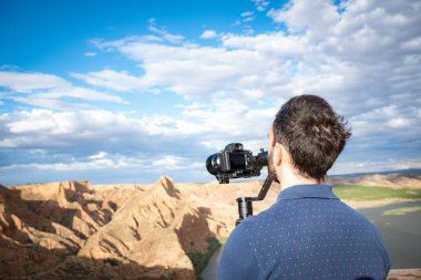 Genç sinemacı, büyük bir nehir ve bataklıklarla kanyondaki doğal manzarayı filme alıyor.