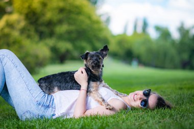 Güzel Yorkshire 'lı genç bir kadın çimen ve ağaçlarla dolu bir bahçede poz veriyor ve sempatik bir şekilde oynuyor..
