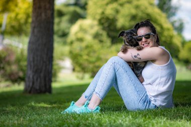 Güzel Yorkshire 'lı genç bir kadın çimen ve ağaçlarla dolu bir bahçede poz veriyor ve sempatik bir şekilde oynuyor..