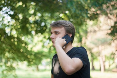 Genç bir iş adamı ayakta duruyor ve telefonda konuşuyor.