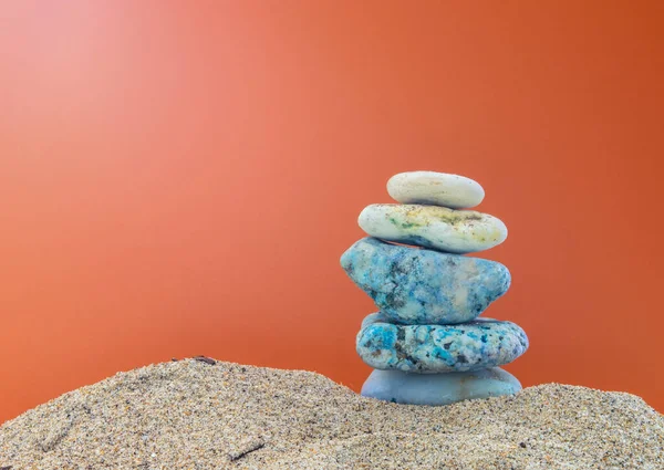 Turuncu arkaplanlı, kumda taş yığını