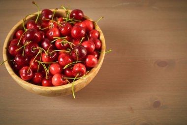 Ahşap zemin üzerinde yeşil bahar kırmızı kirazları seçici odak kirazı