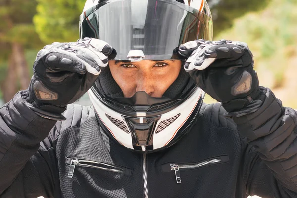 Kaskını tutan motorcunun yakın plan portresi.