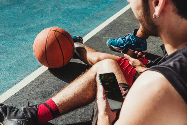 Anak Muda Beristirahat Setelah Pertandingan Basket Dan Menggunakan Smartphone Nya — Stok Foto