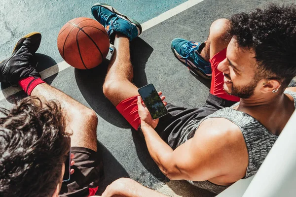 Anak Muda Beristirahat Setelah Pertandingan Basket Dan Menggunakan Smartphone Nya — Stok Foto