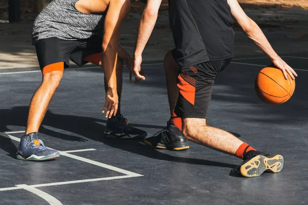 İki tanınmayan insan basketbol oynarken top için kavga eder.