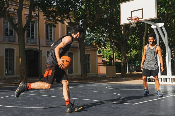 İki genç adam dışarıda basketbol oynuyor.