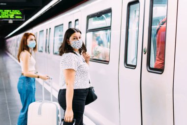Yüzü maskeli genç bir kadın metroyu bekliyor.