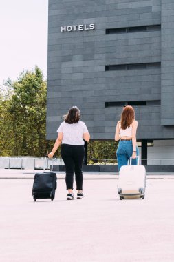 Maskeli iki genç turist, Covid-19 nedeniyle güvenli bir mesafede otellerine doğru yürüyorlar.