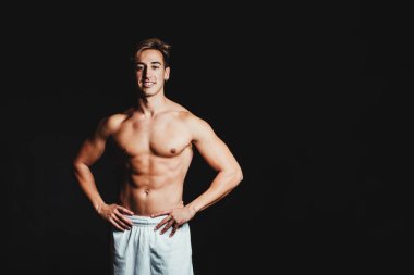 Siyah arka planda üstsüz kaslı bir adam.