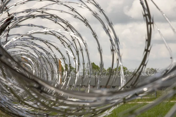 Close up of coiled razor wire on metal fence at abandoned prison yard.