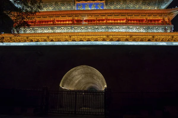 Pedestrian tunnel under front of colorful Drum Tower illuminated at night in Xi\'an, China.
