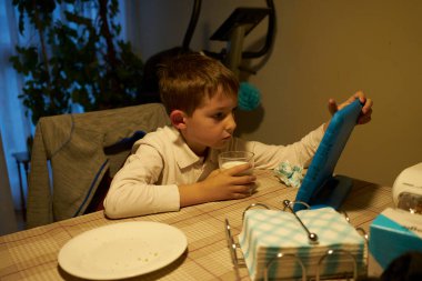 Çocuk abur cubur yerken tablete bakıyor